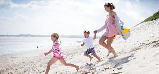 mother and two young children run in the sand toward the water KHM Attorneys at Law Colorado Springs, Castle Rock