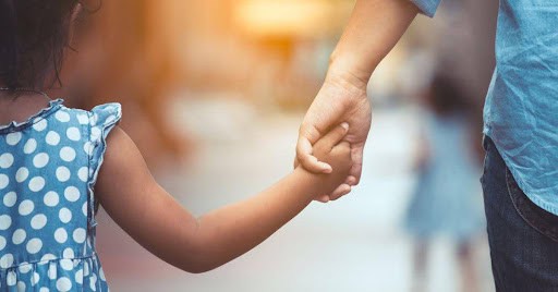 young girl holds dad's hand during a walk outside KHM Attorneys at Law Colorado Springs, Castle Rock