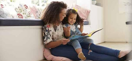 mother reads book to daughter while sitting on the floor in her home KHM Attorneys at Law Colorado Springs, Castle Rock