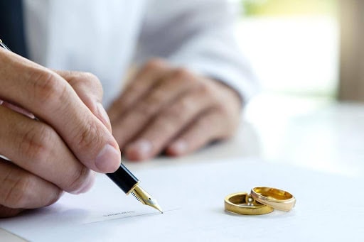 man signs prenuptial agreement while two wedding rings sit on paper KHM Attorneys at Law Colorado Springs, Castle Rock