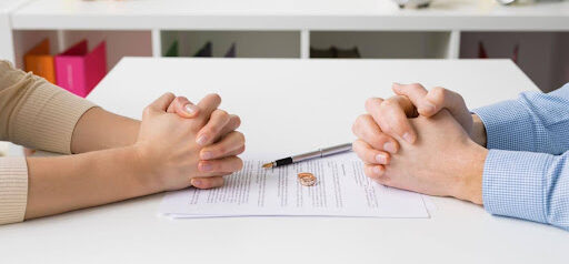 two people sit at table with hands folded with maintenance paperwork between them KHM Attorneys at Law Colorado Springs, Castle Rock