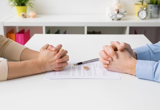 two people sit at table with hands folded with maintenance paperwork between them KHM Attorneys at Law Colorado Springs, Castle Rock