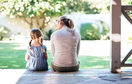 mother speaks to young girl with braids discussing divorce on the patio KHM Attorneys at Law Colorado Springs, Castle Rock