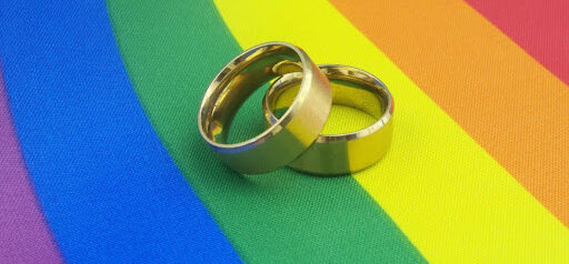 wedding rings on rainbow material showing same sex LGBTQ+ support KHM Attorneys at Law Colorado Springs, Castle Rock