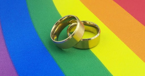 wedding rings on rainbow material showing same sex LGBTQ+ support KHM Attorneys at Law Colorado Springs, Castle Rock