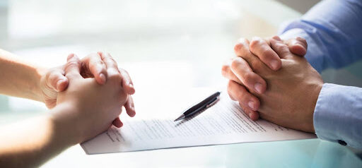 man and woman sit across from table with folded hands as they file for separation KHM Attorneys at Law Colorado Springs, Castle Rock