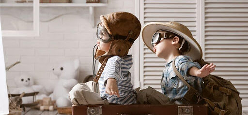 two children play "fly out of state" while wearing goggles and sitting in a suitcase KHM Attorneys at Law Colorado Springs, Castle Rock