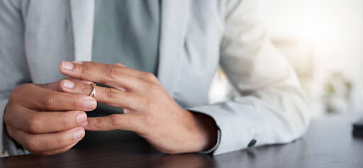 woman in office removes wedding ring as she focuses on healing KHM Attorneys at Law Colorado Springs, Castle Rock