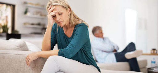man sits on one edge of couch while woman sits on opposite side, both showing signs of stress KHM Attorneys at Law Colorado Springs, Castle Rock
