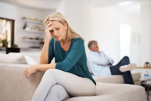 man sits on one edge of couch while woman sits on opposite side, both showing signs of stress KHM Attorneys at Law Colorado Springs, Castle Rock