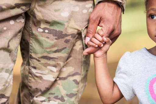 young child holds finger of her father who is in the military KHM Attorneys at Law Colorado Springs, Castle Rock