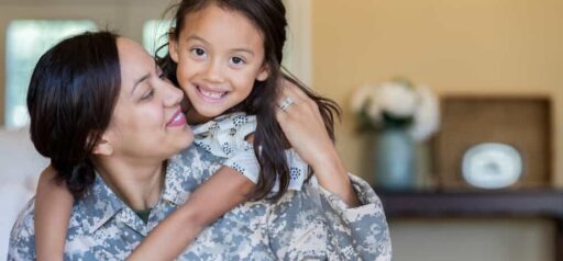 woman wearing military fatigues looks at daughter who is hugging her from her back KHM Attorneys at Law Colorado Springs, Castle Rock