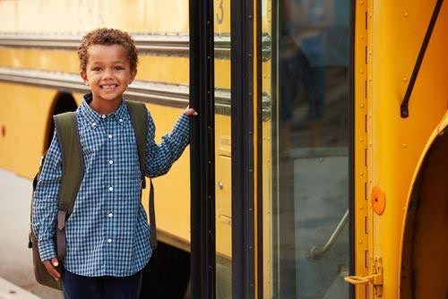 young child poses before getting on school bus KHM Attorneys at Law Colorado Springs, Castle Rock