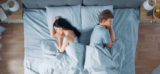 man and woman face opposite sides of bed thinking their marriage might be over KHM Attorneys at Law Colorado Springs, Castle Rock