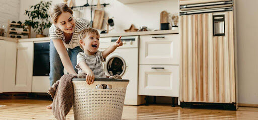 young woman pushes son around in laundry basket in modern home KHM Attorneys at Law Colorado Springs, Castle Rock