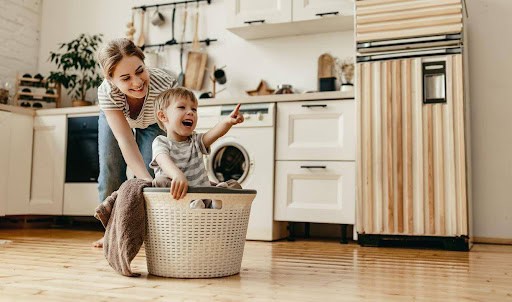 young woman pushes son around in laundry basket in modern home KHM Attorneys at Law Colorado Springs, Castle Rock