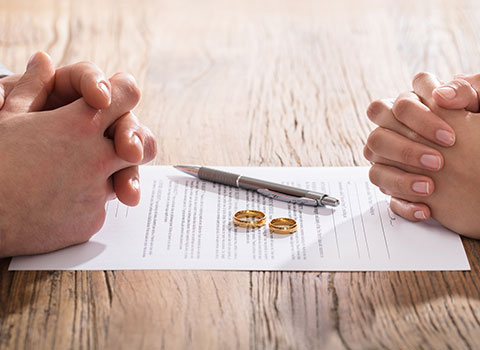 man and woman getting divorced place rings on legal paperwork KHM Attorneys at Law Colorado Springs, Castle Rock