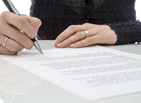 hero image of woman signing legal document KHM Attorneys at Law Colorado Springs, Castle Rock