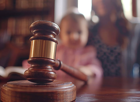 close up of gavel with mother and baby in background KHM Attorneys at Law Colorado Springs, Castle Rock