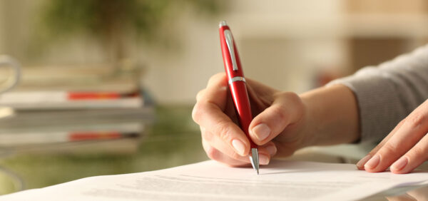 woman signs legal modification paperwork with red pen KHM Attorneys at Law Colorado Springs, Castle Rock
