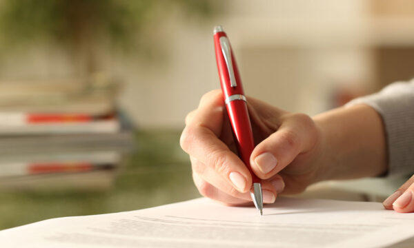 woman signs legal modification paperwork with red pen KHM Attorneys at Law Colorado Springs, Castle Rock