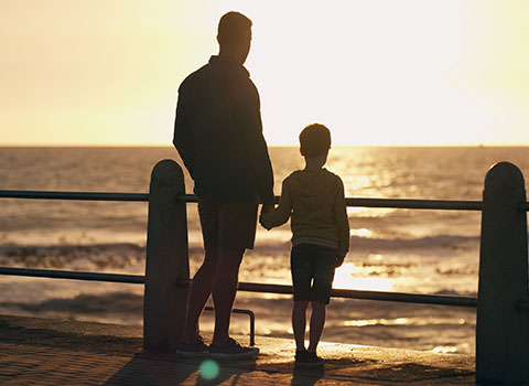 hero size image of father and son holding hands while watching sun set along beach KHM Attorneys at Law Colorado Springs, Castle Rock