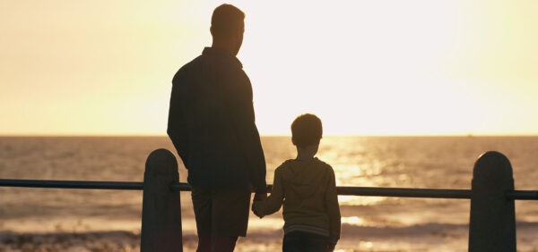 hero size image of father and son holding hands while watching sun set along beach KHM Attorneys at Law Colorado Springs, Castle Rock