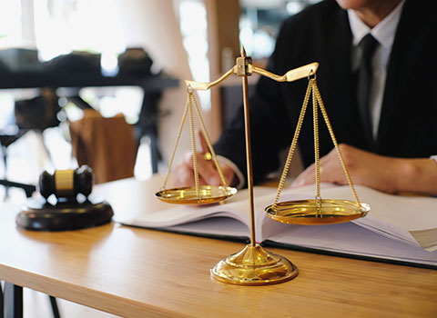 lawyer sits at desk with legal scale in foreground KHM Attorneys at Law Colorado Springs, Castle Rock